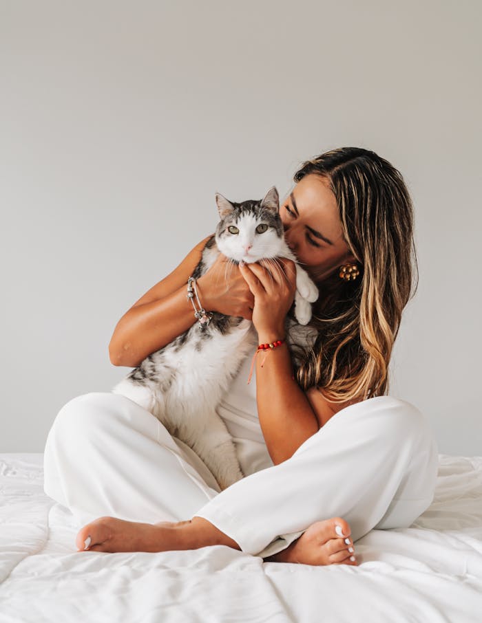 A woman lovingly holds a tabby cat in a serene indoor environment, exuding warmth and comfort.